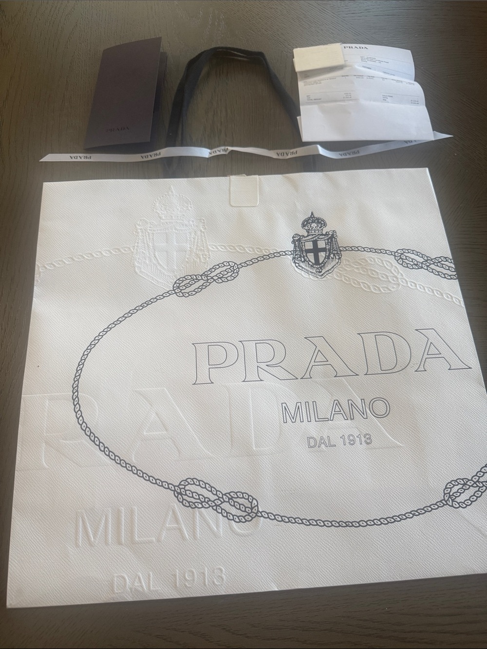 Prada White Milano Embossed Crest Shopping Bag with ribbon and receipt holder.